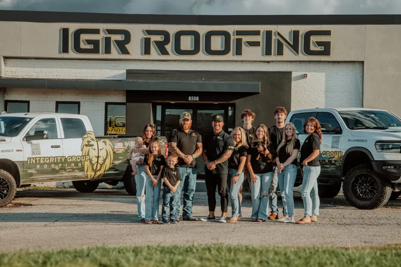 IGR Roofing team standing in front of their office building with company vehicles